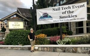 A woman standing in front of a building with a sign.