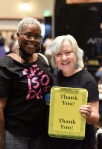 Two women holding a sign that says thank you.