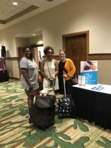 Three women standing next to a table with luggage.