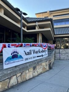 A sign for the nail workshop in front of a building.