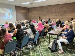 A group of people sitting in front of a projector screen.