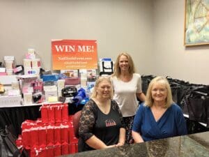Three women standing in front of a table full of cups.