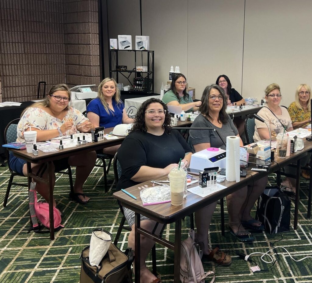 A group of women sitting at tables with pens.