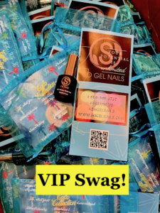 black bottle with gold lid laying on top of blue organza bags with a brochure