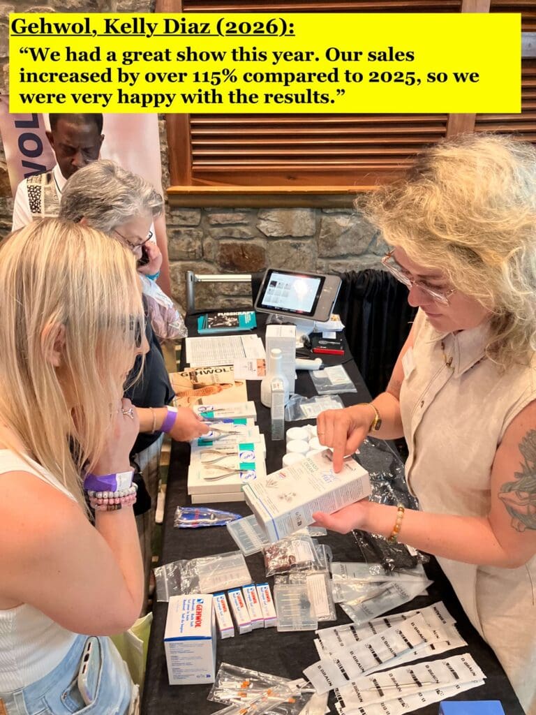 2 women looking at a small Gehwol box that 1 woman is holding in her hand above a table with many different pedicure products & tools on it.